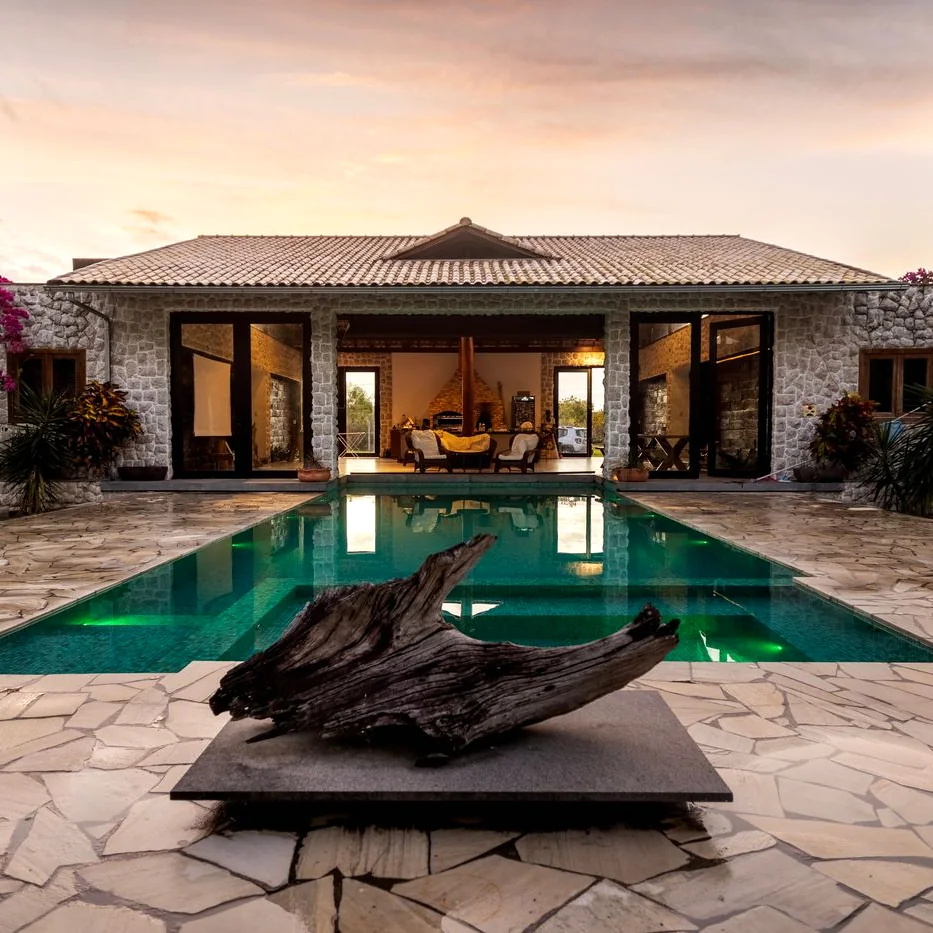 Casa de piedra estilo campestre con piscina al atardecer